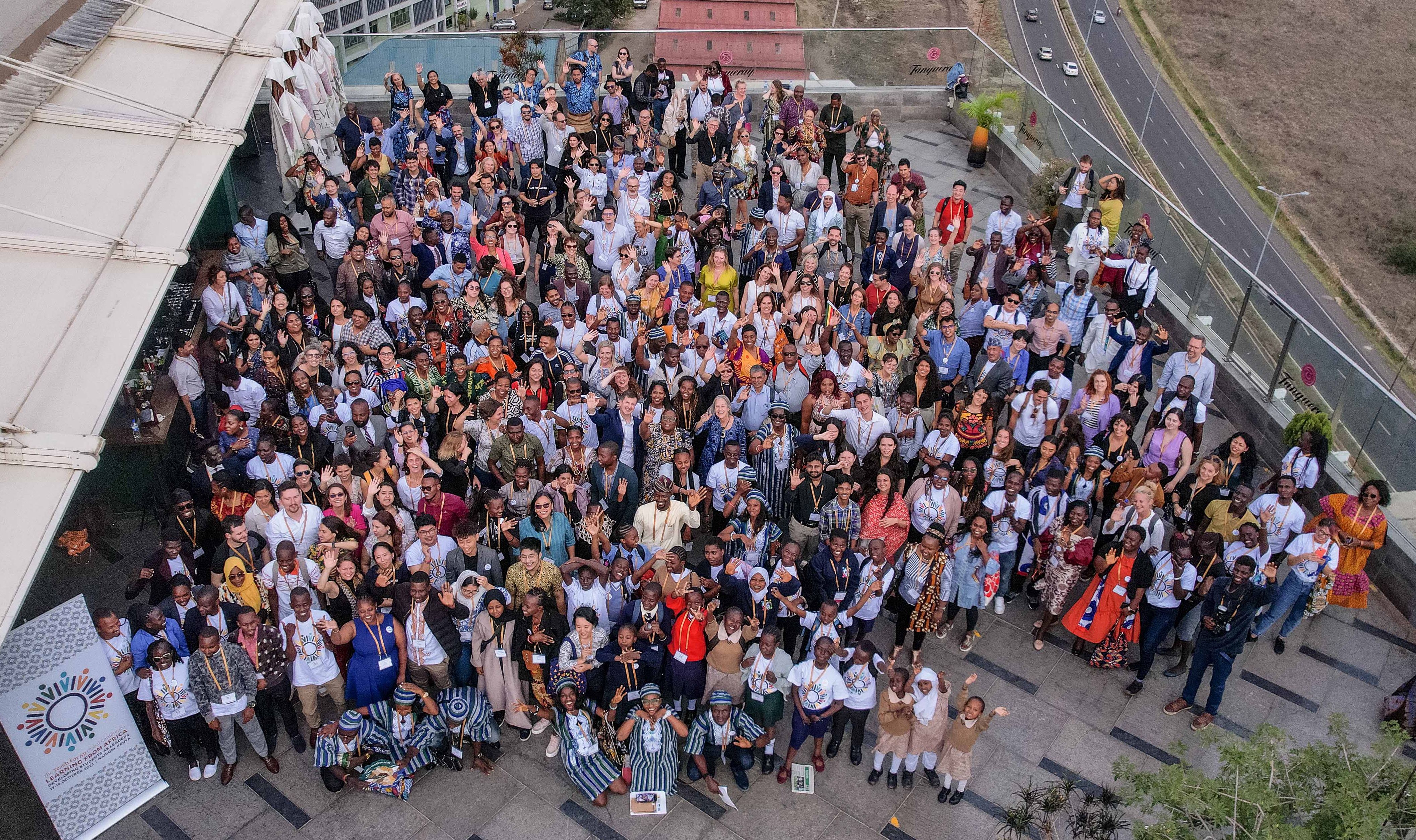 Preview image for the video "2023 Global Conference Highlights" - An overhead shot of a large, diverse group of people on a roof.
