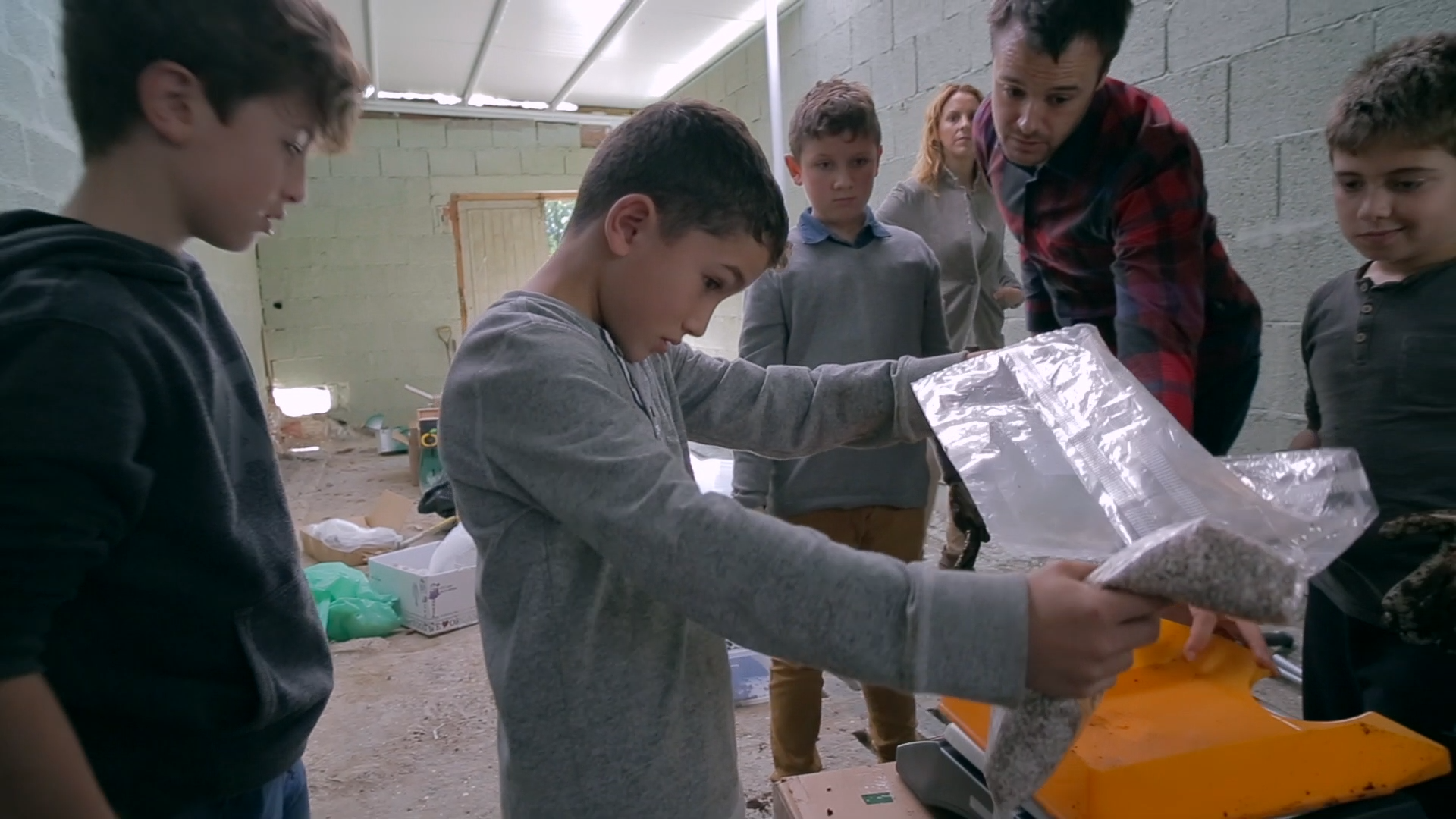 Preview image for the video "Egoitz Etxeandia - Empieza Por Educar" - A boy holds a plastic sheet while two other boys and a young male teachers watch.