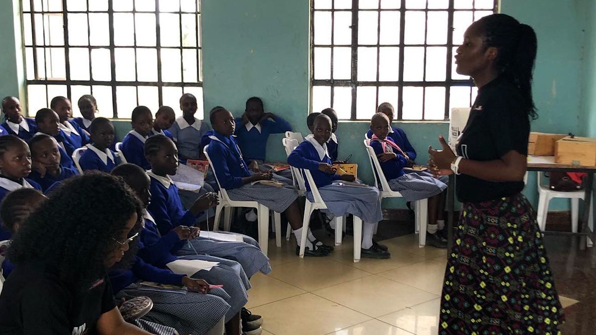 Preview image for the video "Racheal Vichei: Leading Change Through Education in Africa" - A young Black female teacher stands in front of a class of Kenyan students in school uniforms.