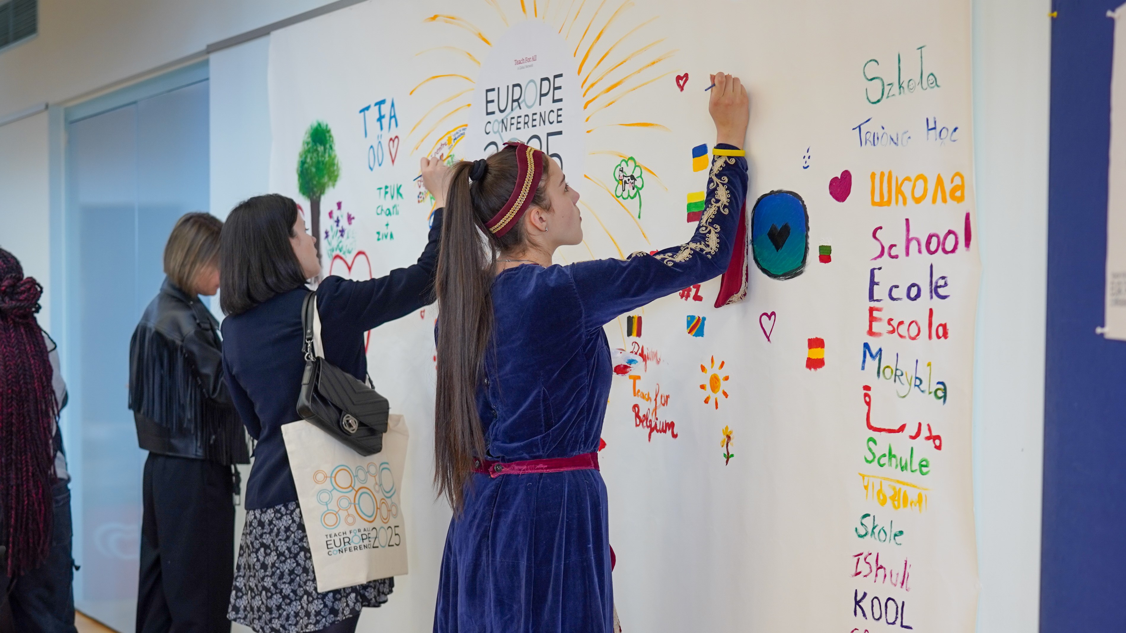 Preview image for the video "Europe Conference 2025 - Highlights" - A young woman with a ponytail writes in marker on a wall that says Europe Conference and is covered in brightly colored writing and drawing.