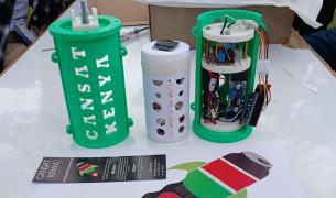 Three 3D-printed CanSat satellite components, labeled "CANSAT KENYA," showing the green outer casing, white inner payload, and internal electronic circuitry.