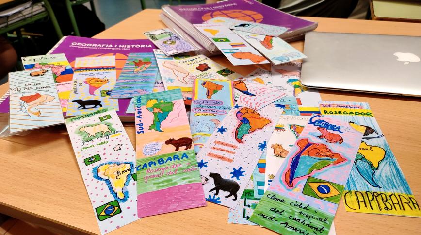 A collection of colorful, hand-drawn maps indicating where capybaras live spread out on a table